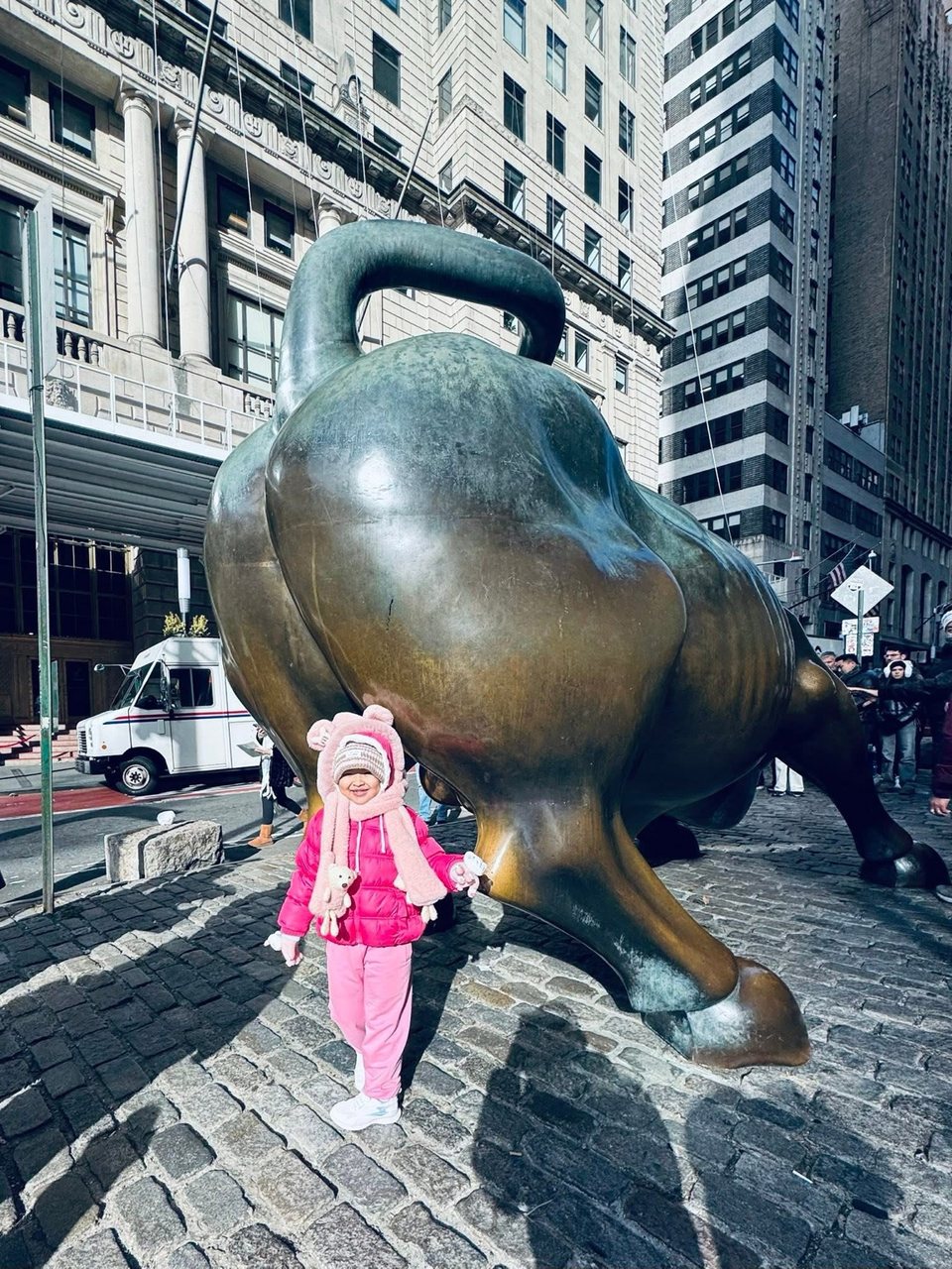 Hồ Bảo Tú mặc áo khoác hồng đứng cạnh tượng bò Wall Street ở New York