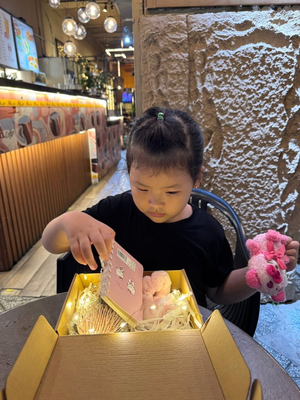 Hồ Bảo Tú mở hộp quà Hello Kitty màu hồng trong quán cà phê